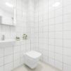 Interior view of the white tiled shower room with toilet